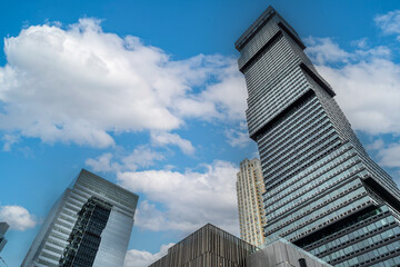 Dramatic perspective of towering Jersey City buildings reaching into a vivid blue sky, reflecting ambition and growth.