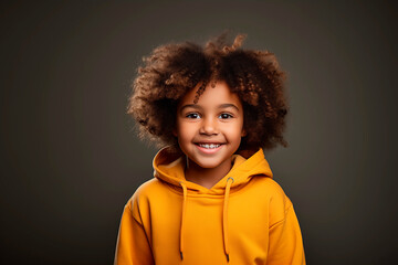 Portrait of a happy black boy looking at camera and smiling wearing a yellow sweatshirt