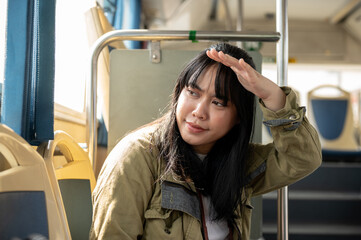 A positive young Asian female passenger is traveling by a city public bus on a sunny day.