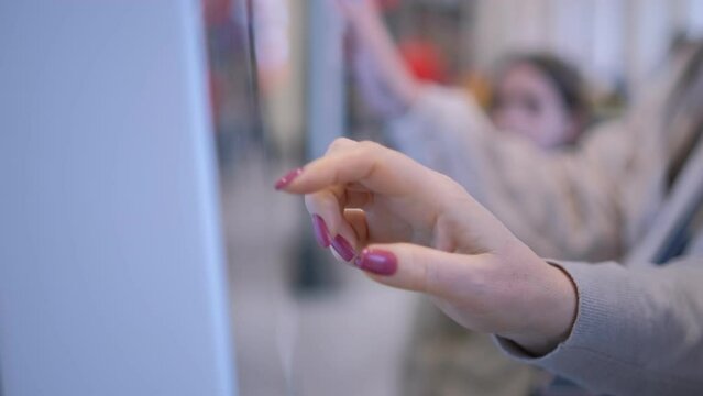 Girl swipes the screen making an order. Woman choosing dessert via self-service machine at fast food restaurant. Girl using touch terminal im restaurant makes a quick order through the self-service.