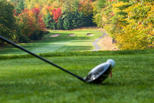 golf ball on a tee on NH golf course with driver on an autumn morning with dew on the fairway 