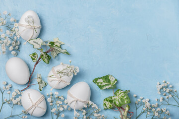 Easter card,background.White Easter eggs decorated with twine and sprigs of gypsophila on a blue background.