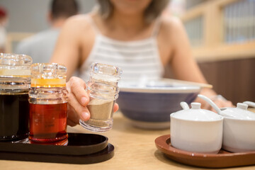 Woman add seasoning to miso ramen in a japanese restaurant