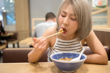 Asian woman enjoying Japanese food inside a Japanese restaurant