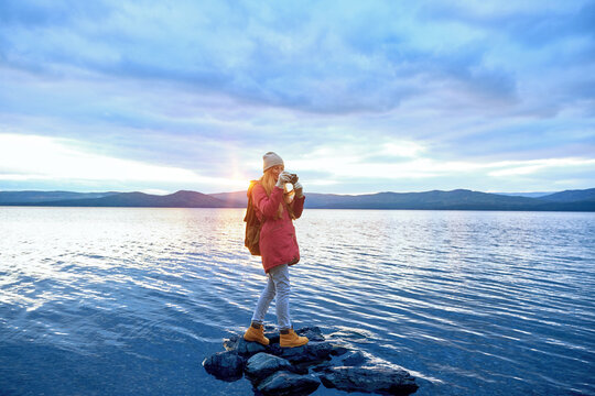 Woman standing on the stones in lake water, enjoying nature