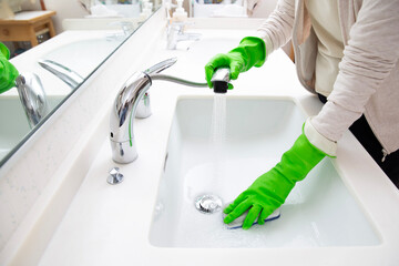 ゴム手袋をつけ洗面台を洗う女性の手元