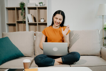  Female manager attending video conference and holding tablet, smatrphone and  cup of coffee on sofa at home