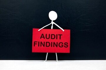 Stick figure holding audit findings placard in black background.