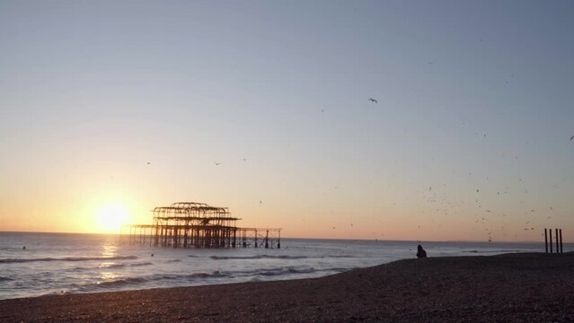 Wide Shot of Silhouetted West Pier, Brighton at Sunset with Birds Flying