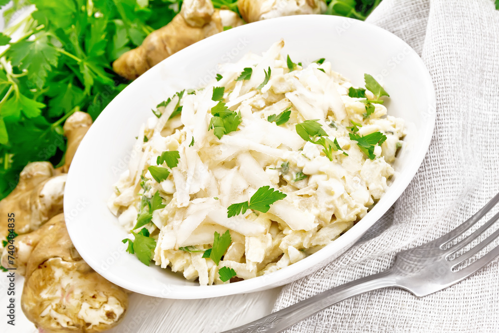 Poster salad of jerusalem artichoke and eggs in plate on light wooden board