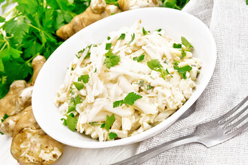 Salad of Jerusalem artichoke and eggs in plate on light wooden board