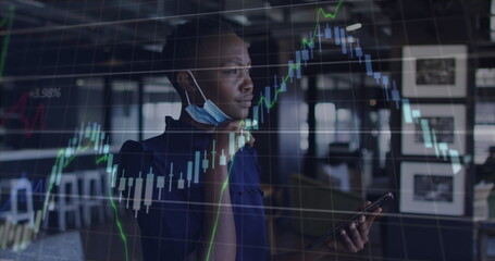 Image of financial data processing over businesswoman with face mask using smartphone in office