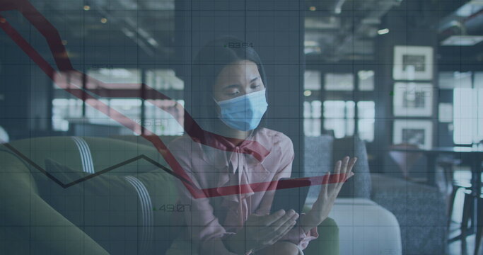 Image of financial data processing over businesswoman with face mask using smartphone in office
