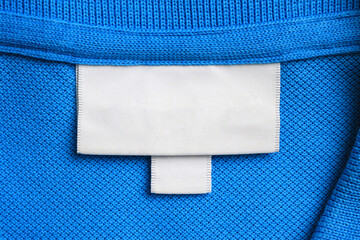 Blank white laundry care clothes label on blue shirt fabric texture background