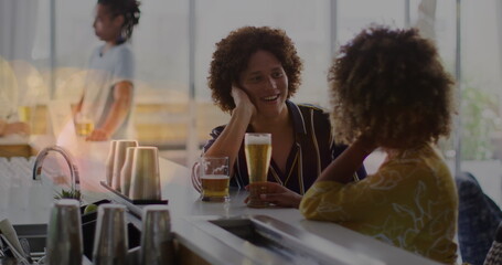 Image of light spots over happy diverse friends drinking beer