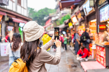 Young female tourist taking a photo of the Ciqikou ancient town in Chongqing, China