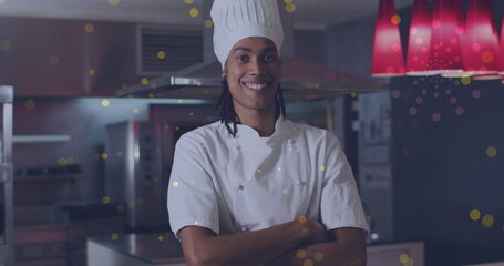 Image of spots over happy biracial male chef with arms crossed