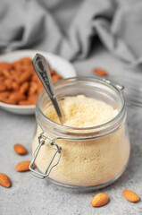 Fresh almond flour in a  glass jar and almonds