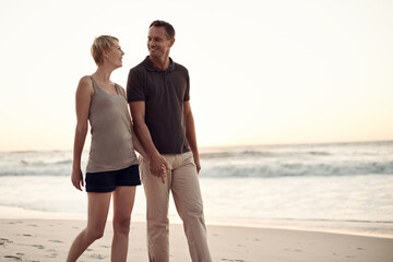 Couple, beach and walking evening on holiday for marriage connection in paradise or honeymoon, sunshine or together. Man, woman and smile at sunset in California for stress relief, explore or break