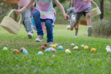 Group of children happily runs around pick up Easter eggs in the park, Easter egg hunt concept,...