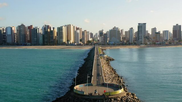 Aerial view of footbridge with people walking around, from the sea to the city with many buildings in the background, Fortaleza, Ceara, Brazil