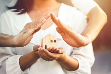 people hand holding miniature wooden house model for banking housing mortgage real estate rent...