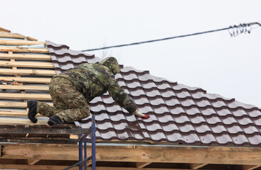 Workers install tiles on the roof of a house in winter