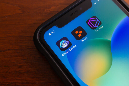 Vancouver, CANADA - Feb 14 2024 : Github Copilot, Replit and Tabnine icons seen in iPhone screen. Generative AI technology, productivity and AI cloud computing concept
