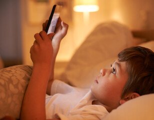 Boy, kid and tablet in bedroom at night for typing, reading or online game with app in family home....