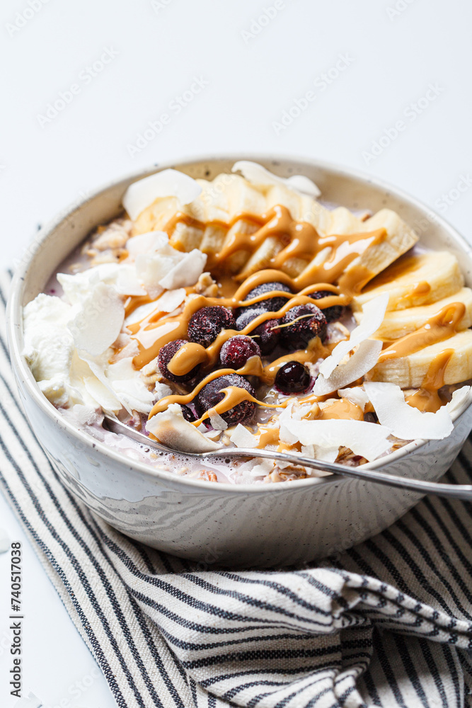 Wall mural Overnight oatmeal with banana, berries, coconut chips and peanut butter.