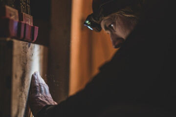 Close-up of Man drilling in wood in low light with headlamp © Cavan