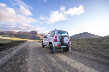 Fototapeta na wymiar Rear view of small 4x4 on dirt road driving toward mountain highlands