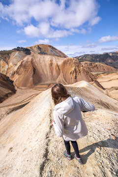 View from top of young woman walking downhill on sand dune