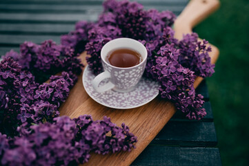 Cup of tea on a wooden board with purple lilac