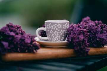 Cup of tea on a wooden board with purple lilac
