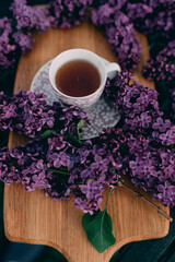 Cup of tea on a wooden board with purple lilac