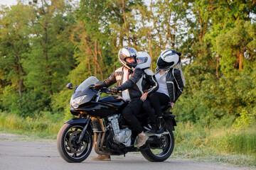 Fototapeta na wymiar A young family with a teenage child is riding a motorcycle