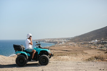 Young man adjusting helmet on four wheeler atv by coastal landscape © Cavan
