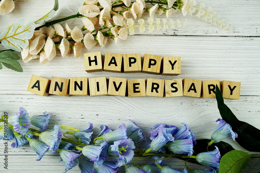 Poster Happy Anniversary alphabet letters with flowers bouquet on wooden background