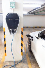 Generic electric vehicle EV hybrid car is being charged from a wallbox on a contemporary modern...