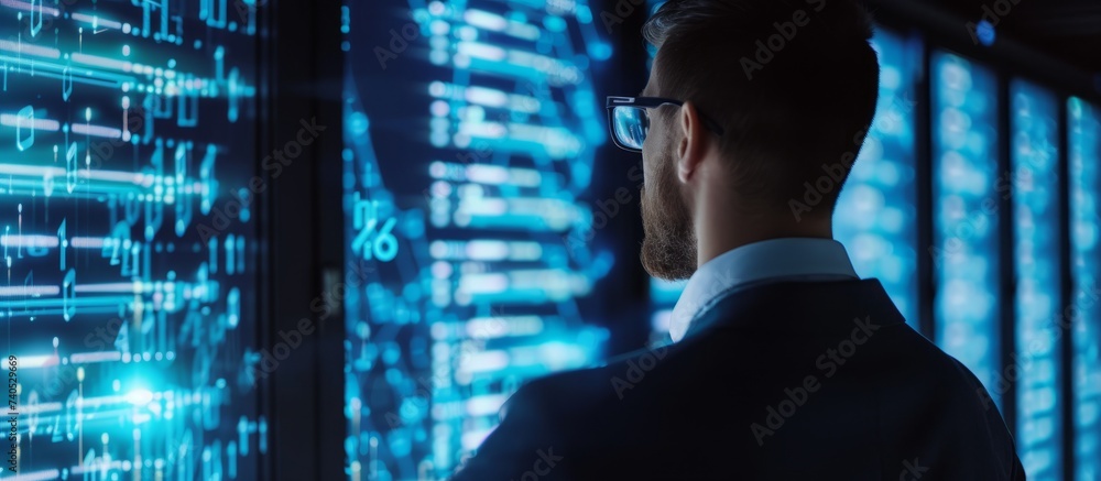 Poster focused businessman in stylish suit analyzing data on computer screen in modern office