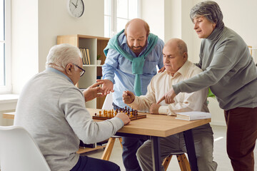 Group of seniors playing board games in retirement home. Several old people playing chess to...