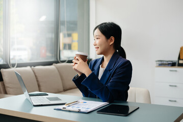 Confident Asian woman with a smile standing holding notepad and tablet at the office.