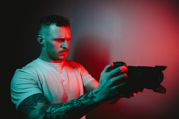 Solo Photographer Grasping Camera, Bathed in Dynamic Red and Blue Lights in Remote Environment