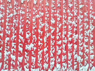 A fence made of galvanized corrugated board in the snow In the village after a snowfall. Abstract background, pattern, texture, place for text and copy space