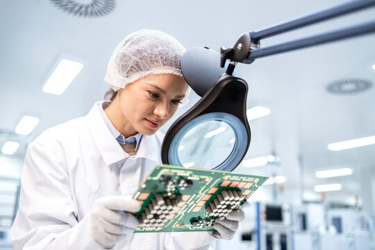 Experienced female technologist working in micro chip production industry and checking quality of electronics parts.