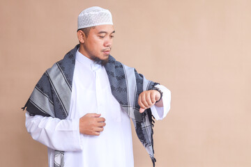 Asian Muslim man checking his watch waiting for iftar time during ramadan.
