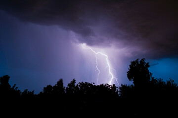 beautiful lightning during a thunderstorm at night in a forest that caused a fire, against a dark...