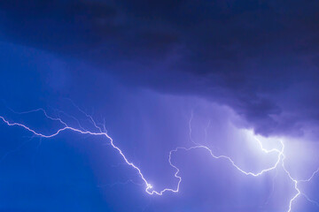 beautiful lightning during a thunderstorm at night in a forest that caused a fire, against a dark...