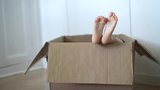 Zoom on child feet moving with a music into a big box, preparing to move house, white background. . High quality FullHD footage